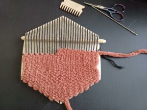 The rust-coloured weave fills the bottom half of the loom, and is now working upwards approximately four rows but only halfway across the loom now.
