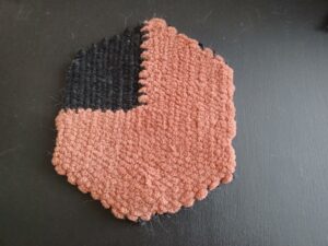 The weave is sitting by itself against a black background. All the ends are now sewn in, and it looks like a completed pie chart.