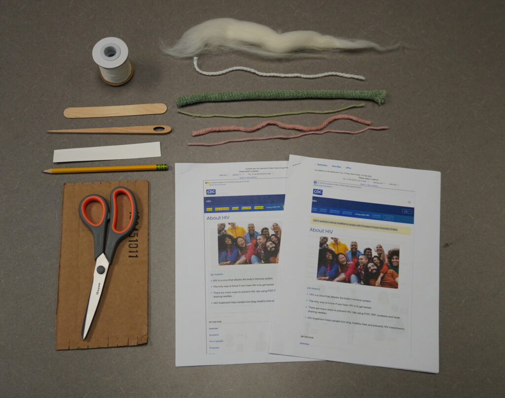 Supplies arranged on a table: a cardboard loom, scissors, a popsicle stick, a small strip of card stock, warp thread, a tapestry needle, various yarns, and printed copies of the two versions of the CDC website with highlighted diffs.