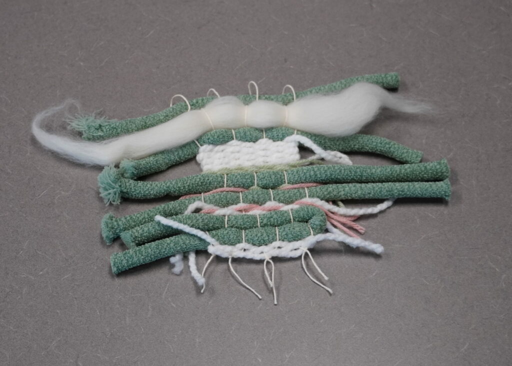 The ends of the tapestry have been tied off and it has been removed from the loom. The top has loops for hanging. The ends are still long and ragged.