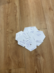 A pile of paper hexagons with reference questions written on them in blue ink. 